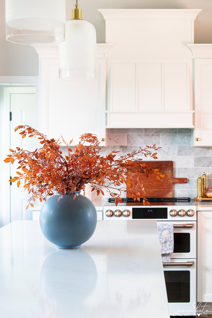 dramatic orange falls stems in a round vase on a kitchen island.