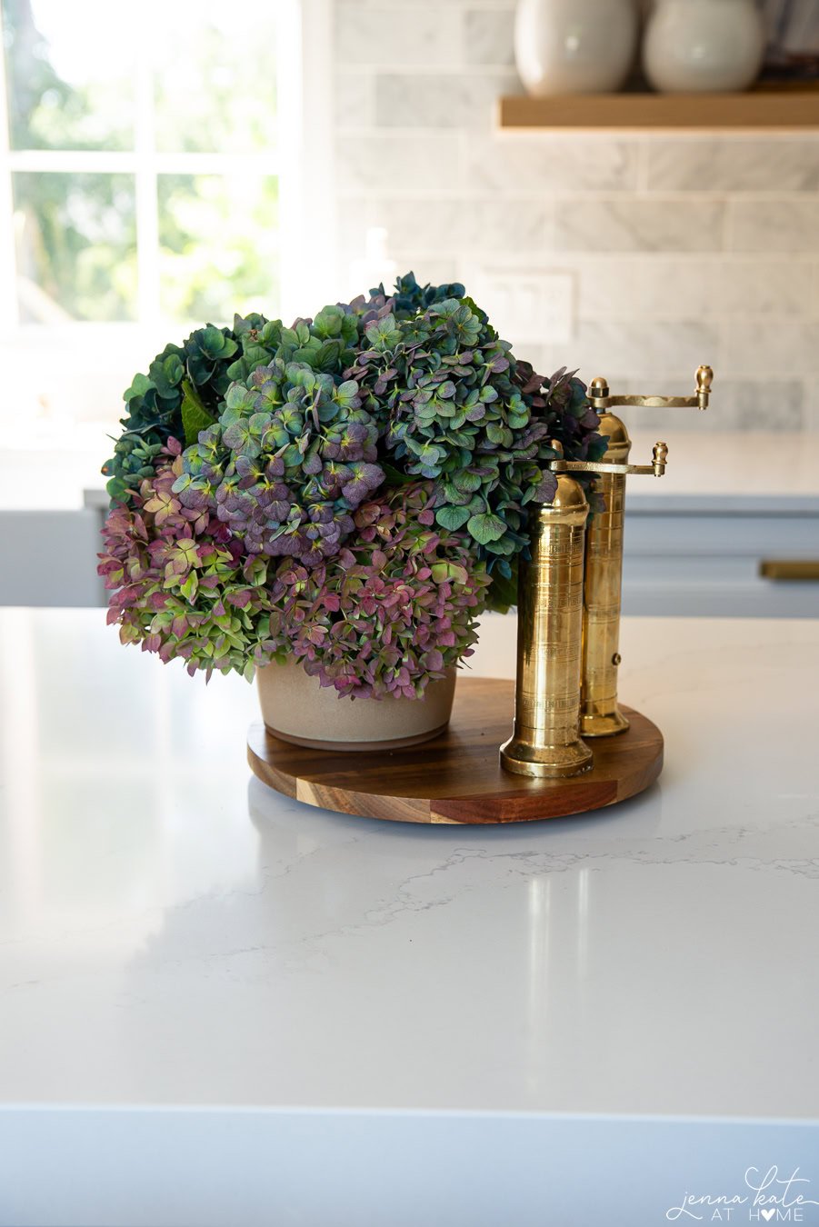 hydrangeas in a vase in shades of deep purple and blue with brass salt and pepper mills next to them.