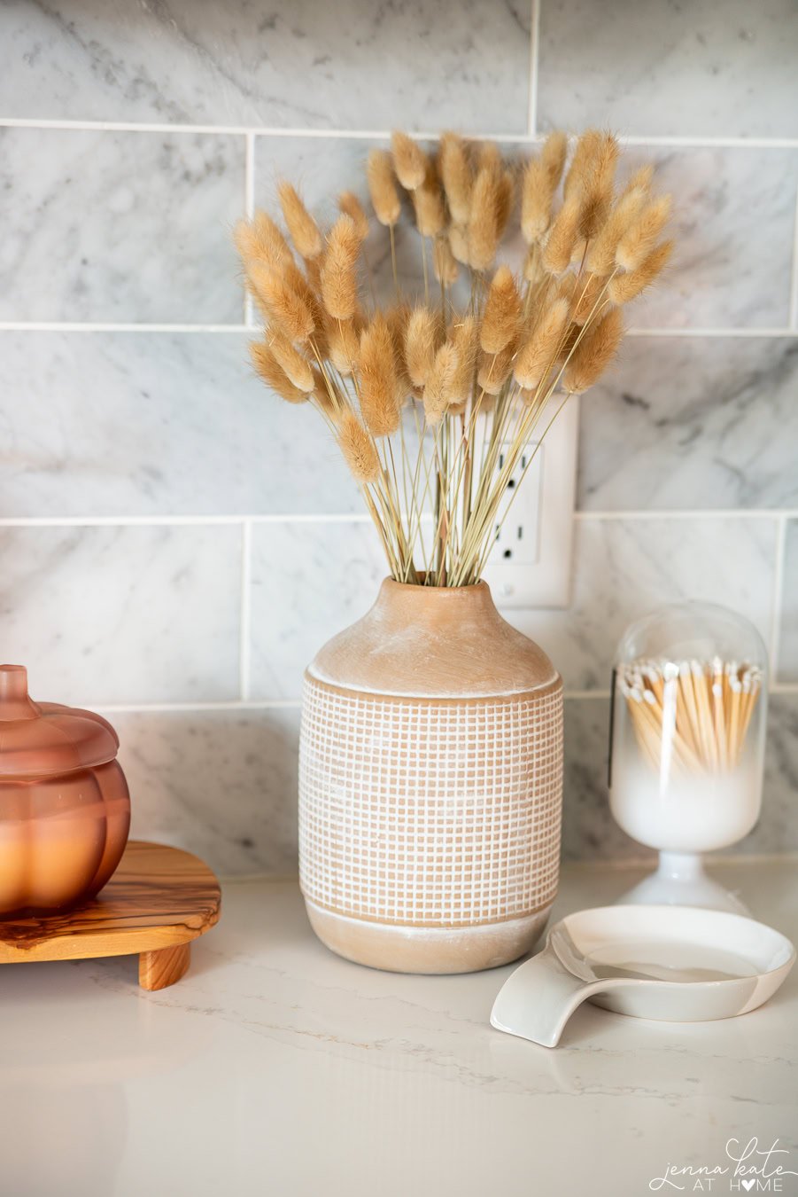 vase of fall stems on a kitchen counter.