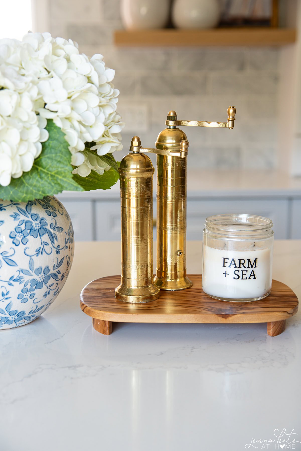 wooden riser styled on a kitchen island with brass salt and pepper mills and a candle.