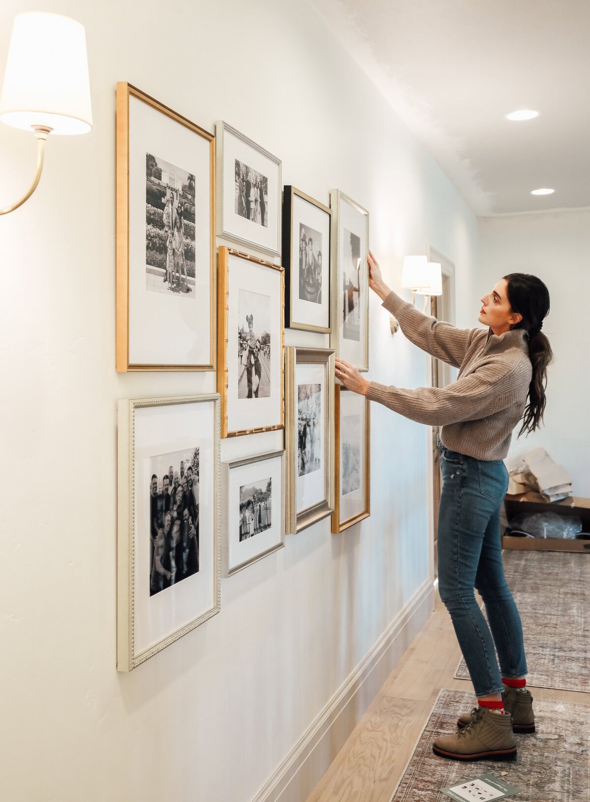 woman hanging art on a hallway gallery wall.