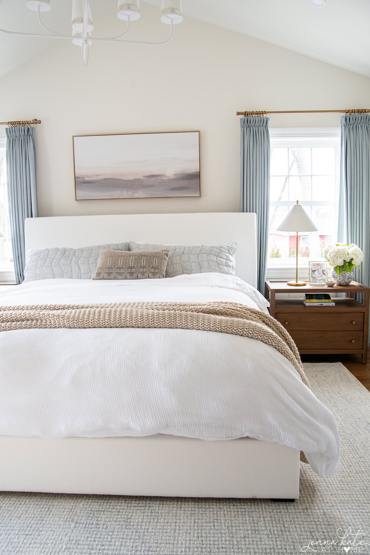 white bed with white bedding and wooden nightstands.