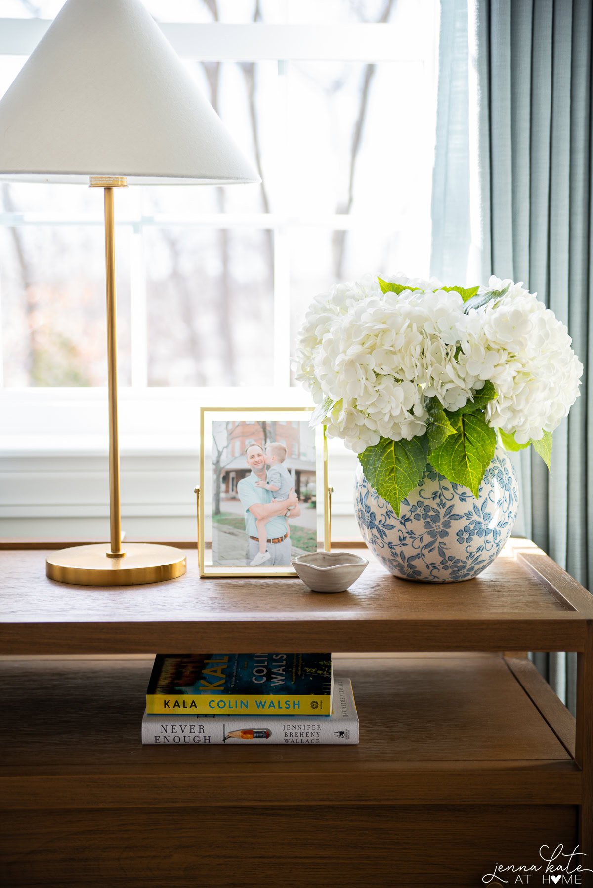 styled nightstand with vase of hydrangeas and a table lamp.