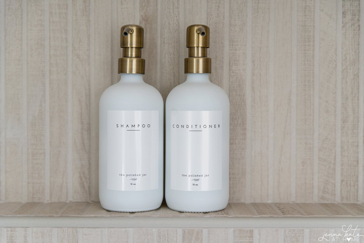 shampoo and conitioner bottles sitting in the niche of the shower.