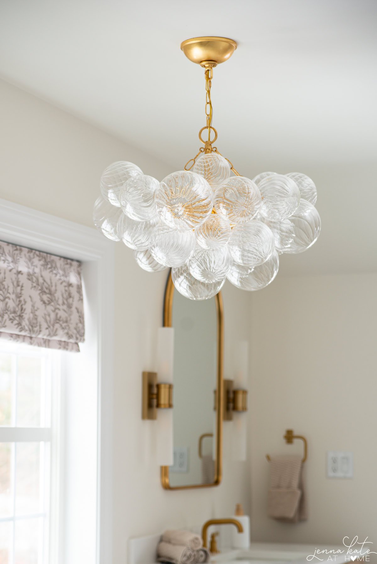 Bubble glass chandelier over tub adding statement lighting in elegant primary bathroom.