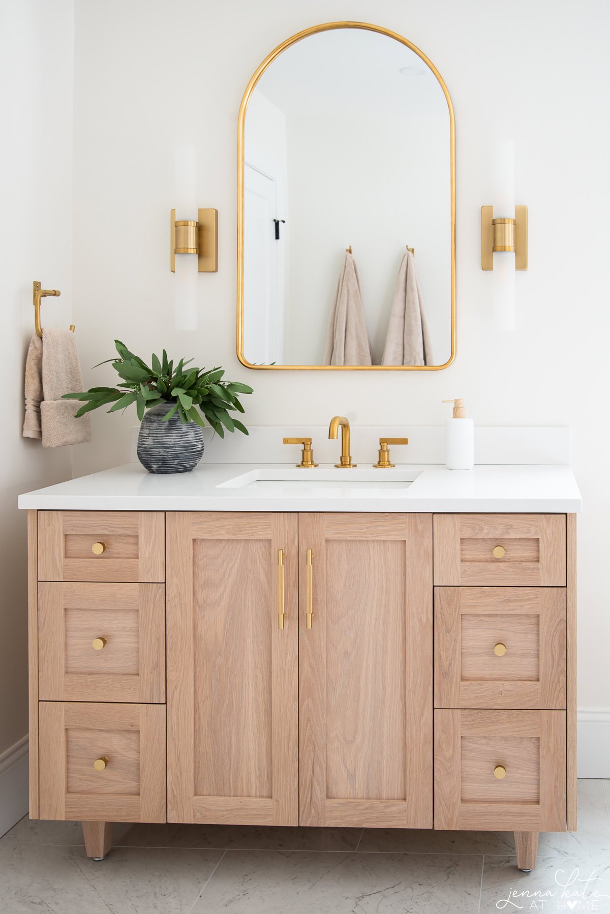 White oak bathroom vanity with brass hardware and quartz countertops in a modern bathroom.