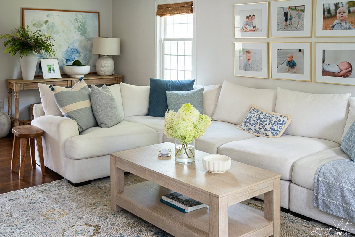 Another view of the living room with a gallery wall of family photos behind the couch and a console table with a large piece of art on the other wall.