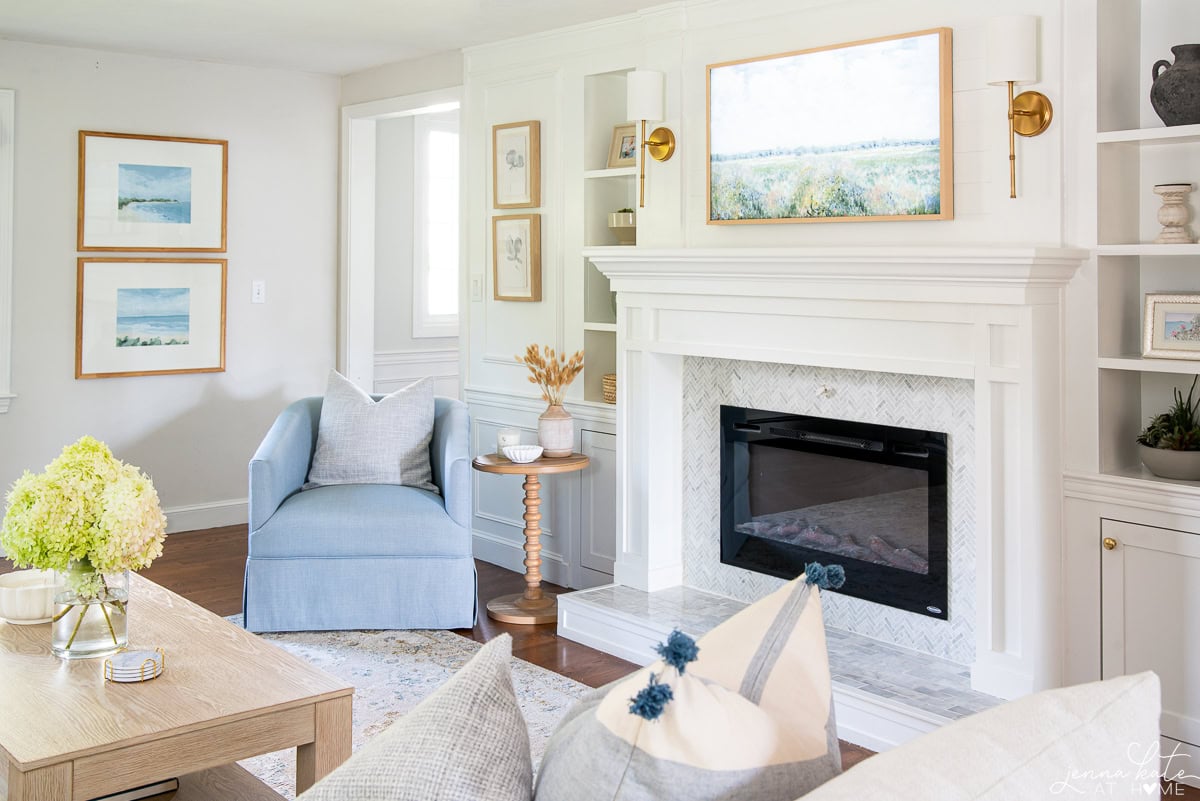 View of the living room facing the fireplace with the blue chair and a spindle base accent table.