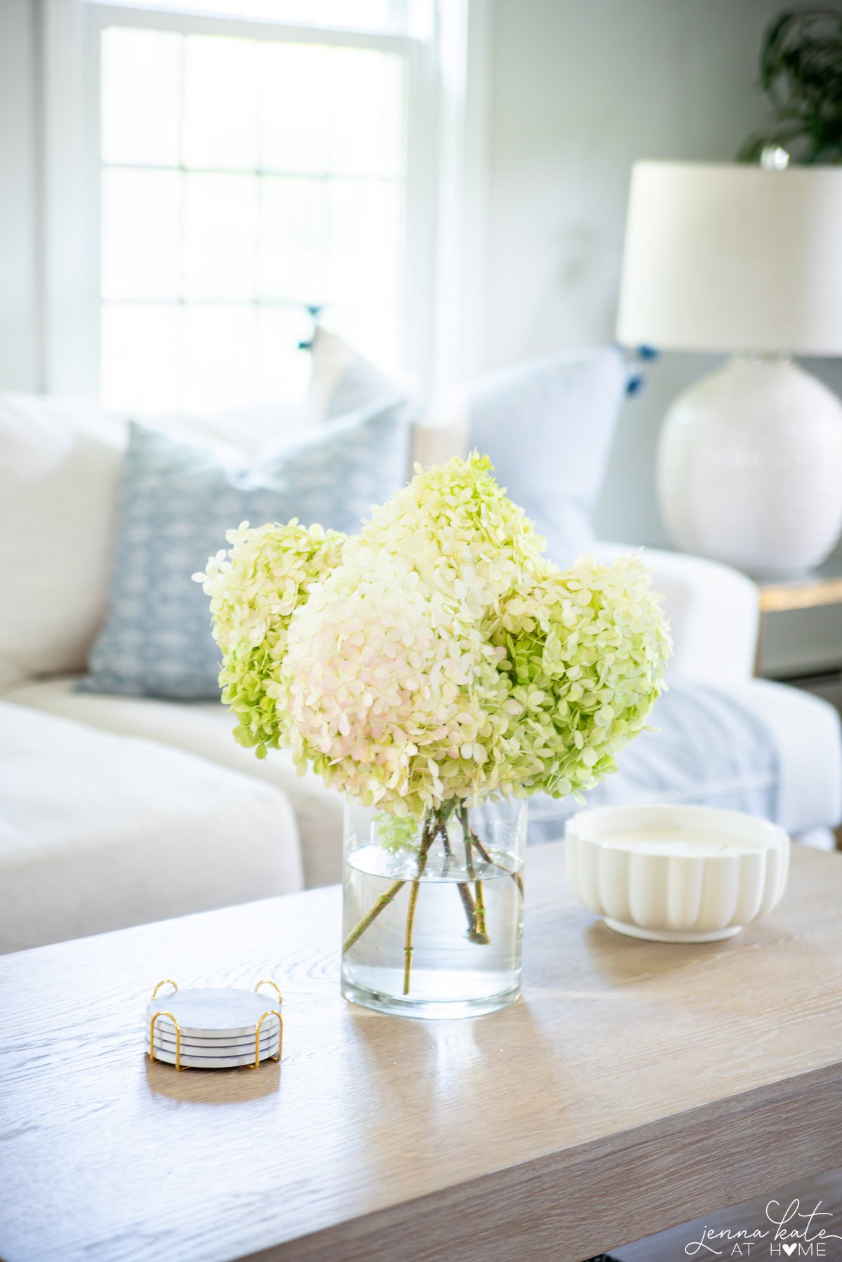 vase of hydrangeas on a light coastal style coffee table.