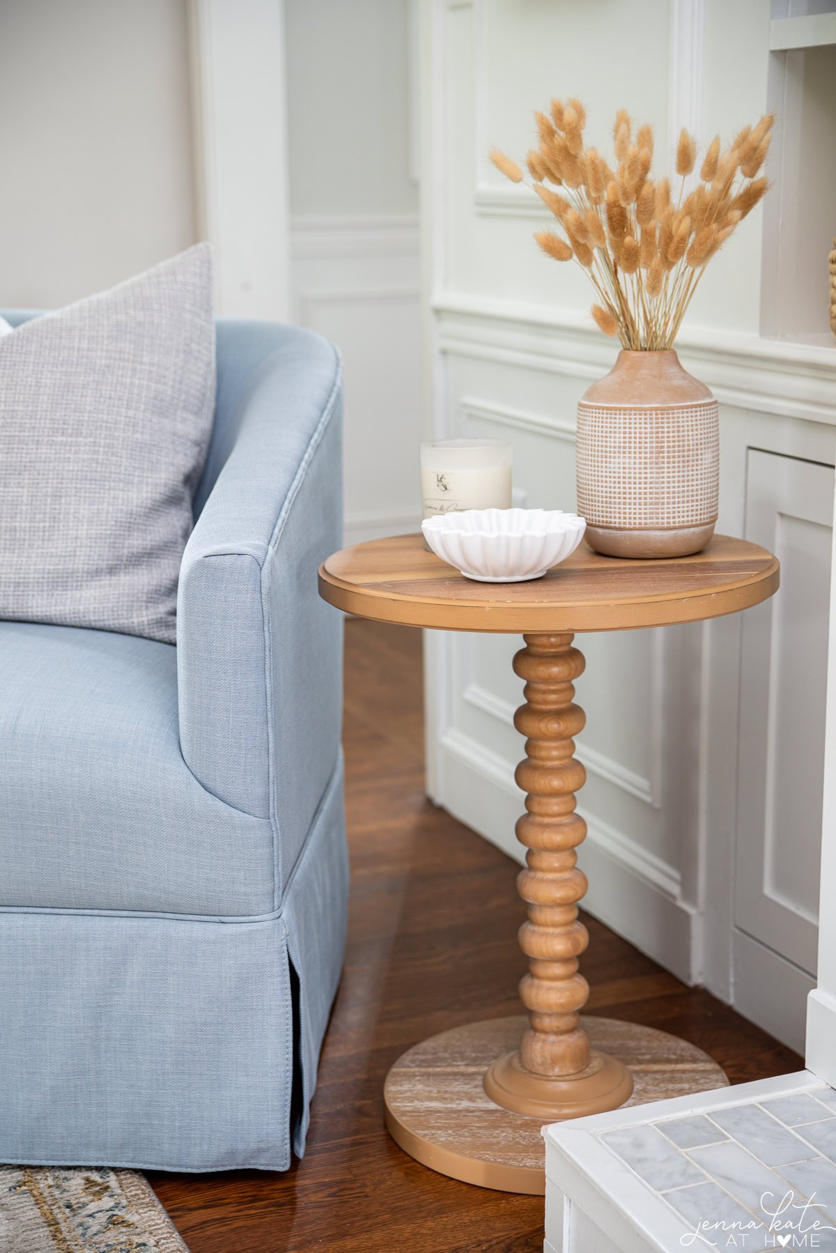 Accent table with some decorative pieces including a vase with pampas stems.