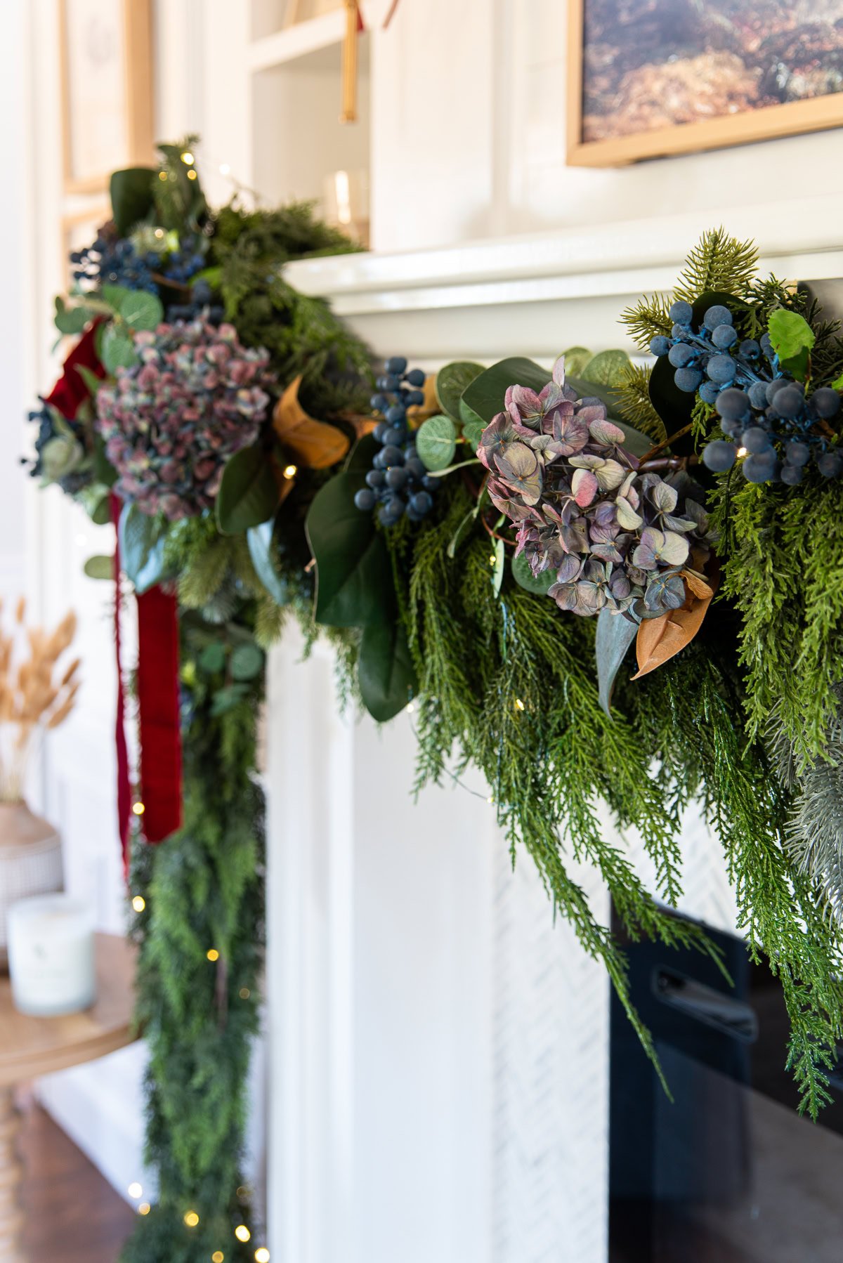Close up of Christmas garland with dried blue hydrangeas, faux blueberries and magnolia leaves,