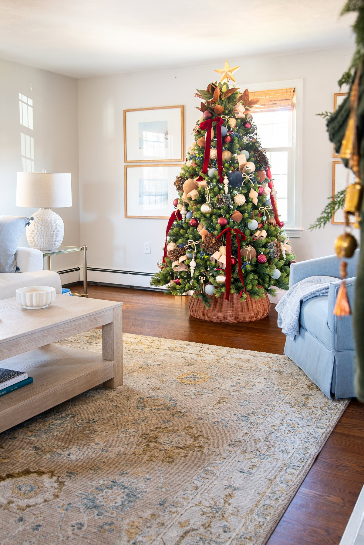 Neutral christmas tree with large red bows hanging from branches.