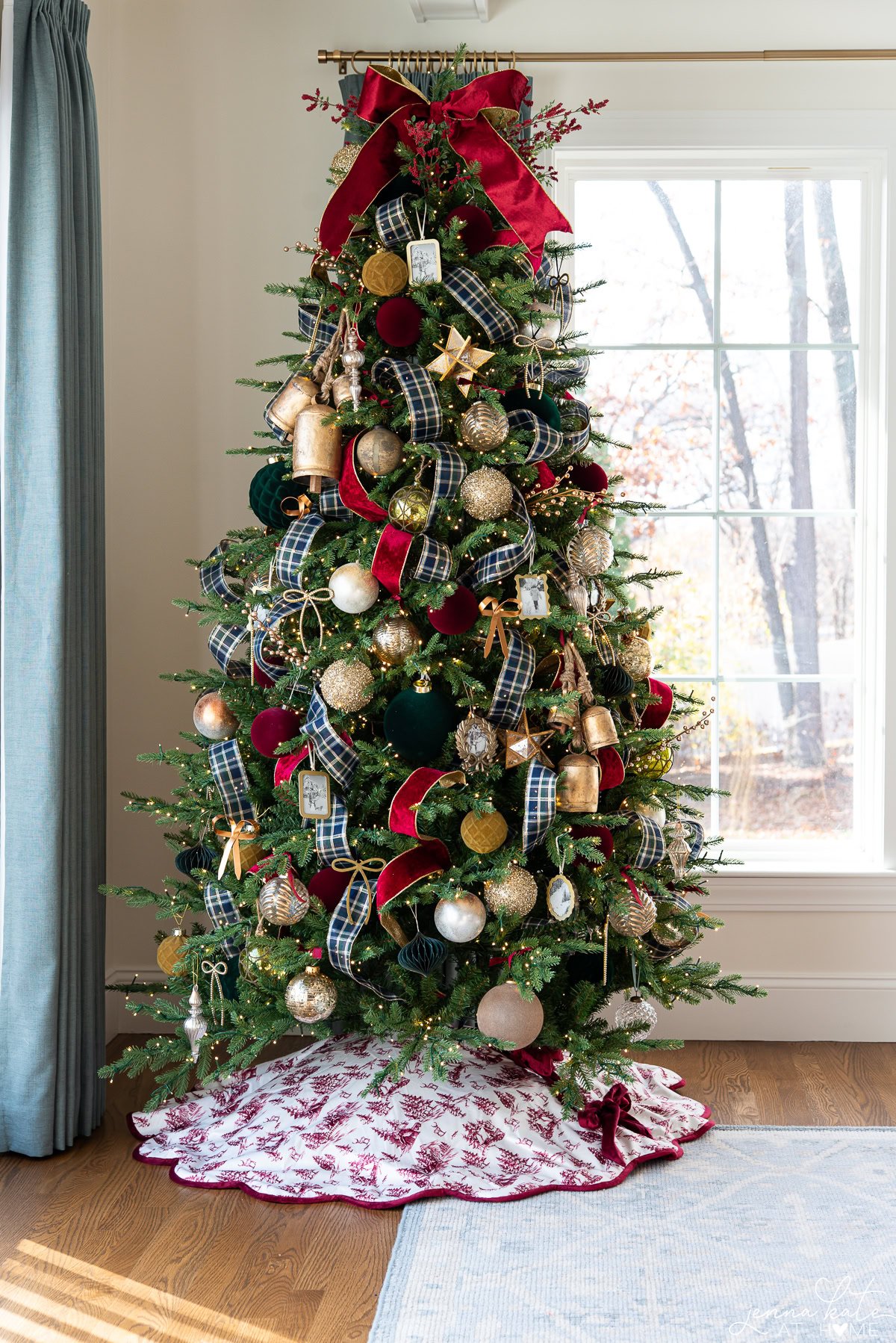 Christmas with large red bow topper, blue plaid ribbons and red and gold ornaments.
